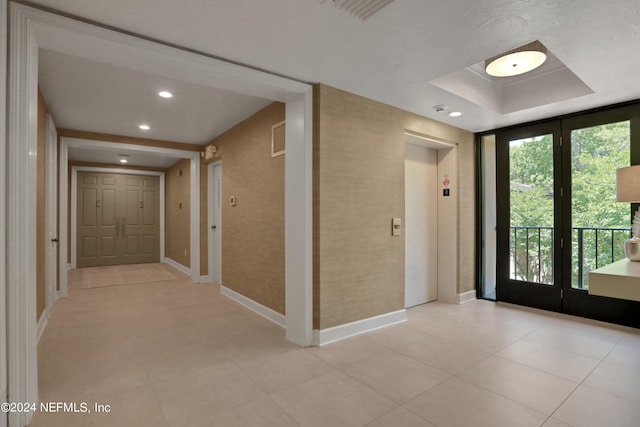 entryway with elevator and a tray ceiling