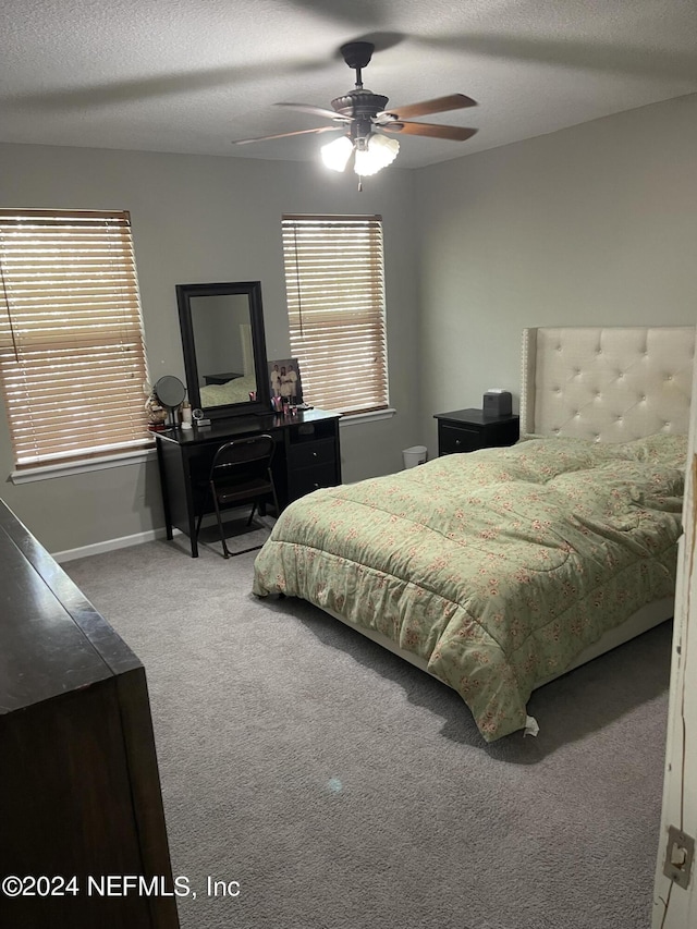 bedroom with multiple windows, ceiling fan, carpet floors, and a textured ceiling