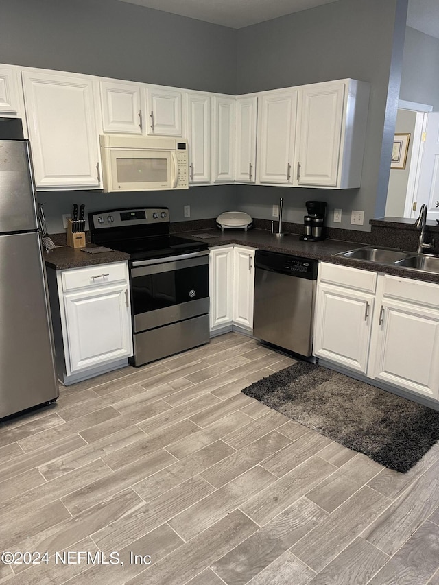 kitchen featuring stainless steel appliances, white cabinetry, and sink