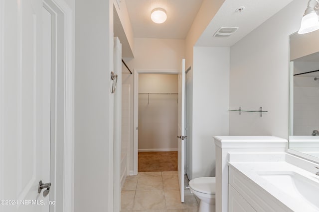 bathroom featuring tile patterned flooring, toilet, visible vents, vanity, and a spacious closet