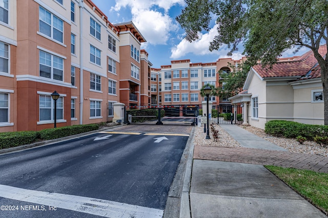 view of road with street lights, a gated entry, sidewalks, curbs, and a gate