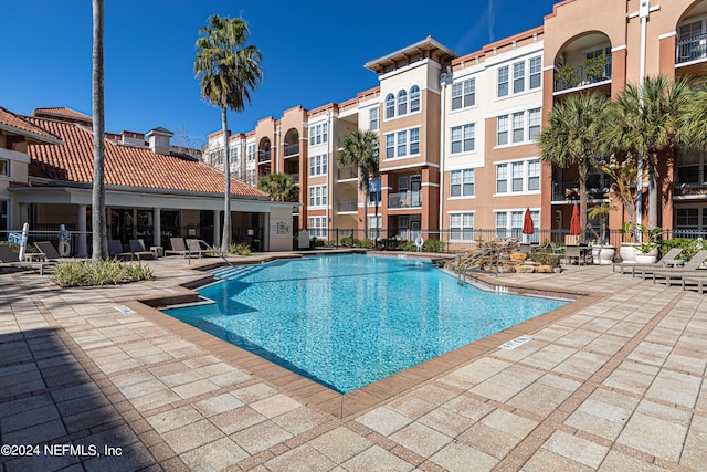 community pool with a patio and fence