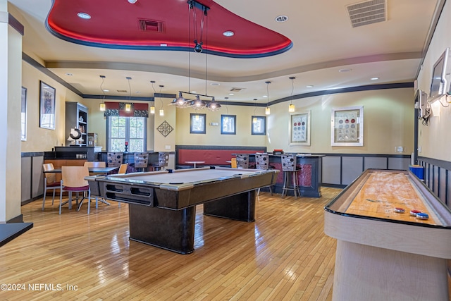 game room with a dry bar, visible vents, a tray ceiling, and wood-type flooring