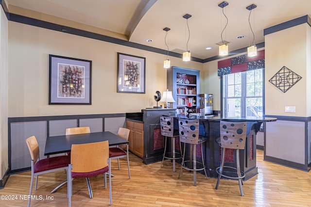 bar featuring pendant lighting, a wainscoted wall, light wood finished floors, recessed lighting, and a bar