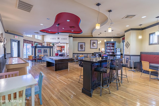 interior space with a bar, light wood-style floors, visible vents, and ornamental molding