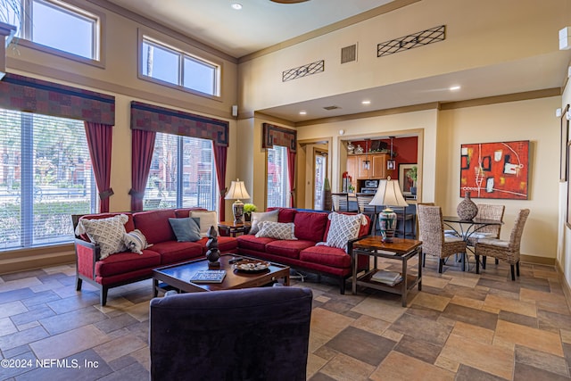 living room with baseboards, visible vents, a towering ceiling, stone tile flooring, and recessed lighting