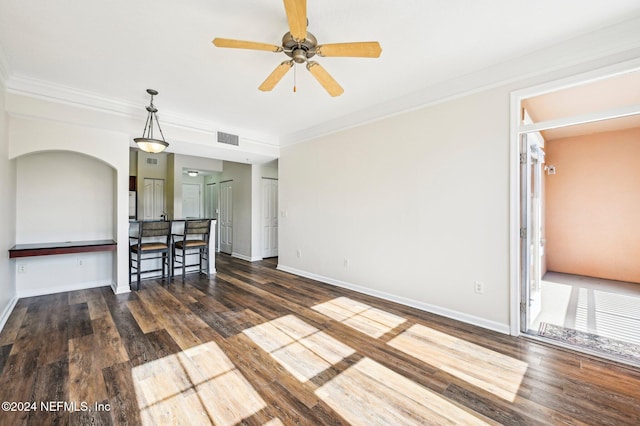 unfurnished living room featuring baseboards, visible vents, a ceiling fan, ornamental molding, and wood finished floors