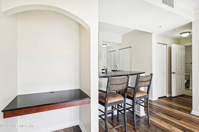 dining space featuring baseboards, visible vents, arched walkways, and dark wood-type flooring