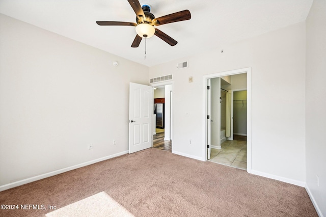 unfurnished bedroom featuring light colored carpet, freestanding refrigerator, visible vents, and baseboards