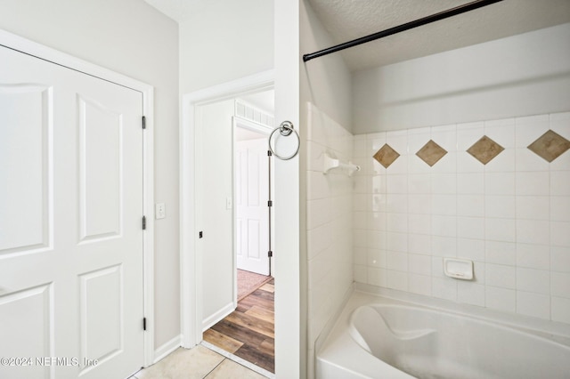 bathroom with  shower combination, a textured ceiling, baseboards, and tile patterned floors