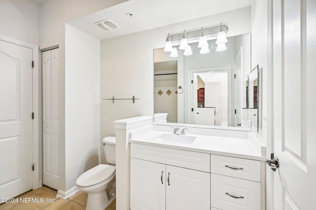 bathroom featuring toilet, vanity, and visible vents