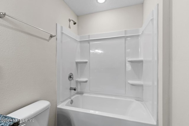 bathroom featuring toilet, shower / bath combination, a textured ceiling, and a textured wall