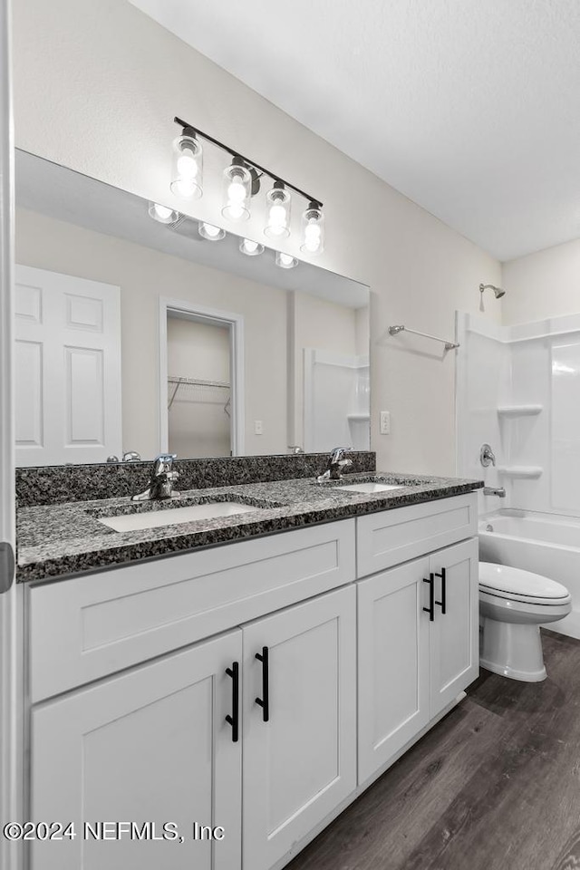 full bathroom with bathtub / shower combination, toilet, wood finished floors, a sink, and double vanity