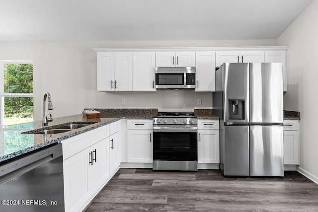 kitchen with dark hardwood / wood-style flooring, sink, dark stone counters, and stainless steel appliances