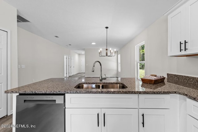 kitchen featuring white cabinets, sink, stainless steel dishwasher, dark stone countertops, and a chandelier