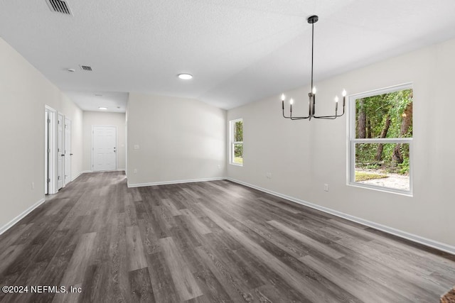 unfurnished dining area with dark wood-style flooring, visible vents, baseboards, vaulted ceiling, and an inviting chandelier