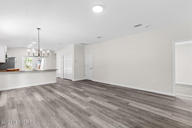 unfurnished living room featuring an inviting chandelier and hardwood / wood-style floors