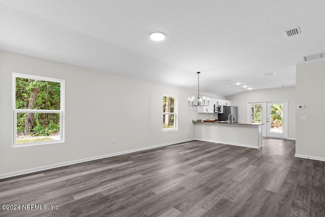 unfurnished living room featuring vaulted ceiling, dark hardwood / wood-style flooring, a chandelier, and french doors