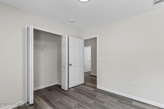 unfurnished bedroom featuring baseboards, a textured ceiling, visible vents, and dark wood-style flooring