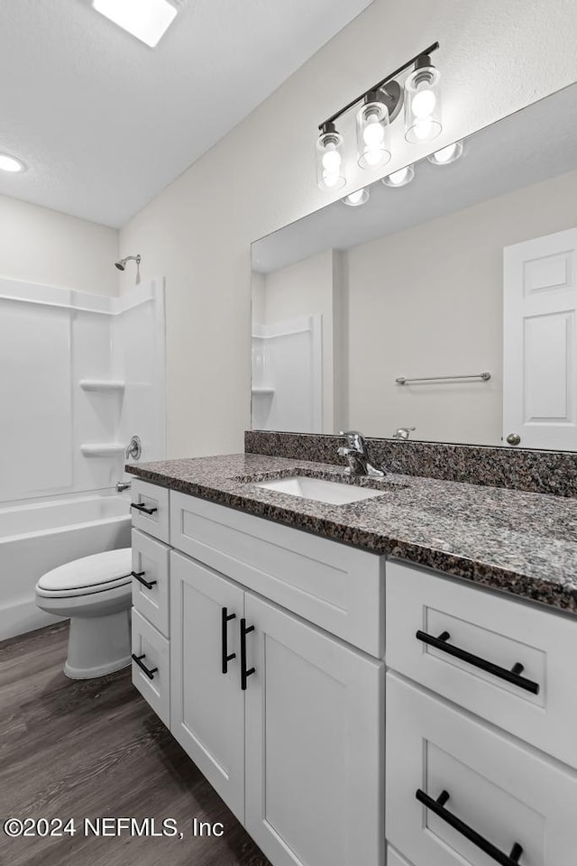 full bathroom with toilet, washtub / shower combination, wood finished floors, and vanity