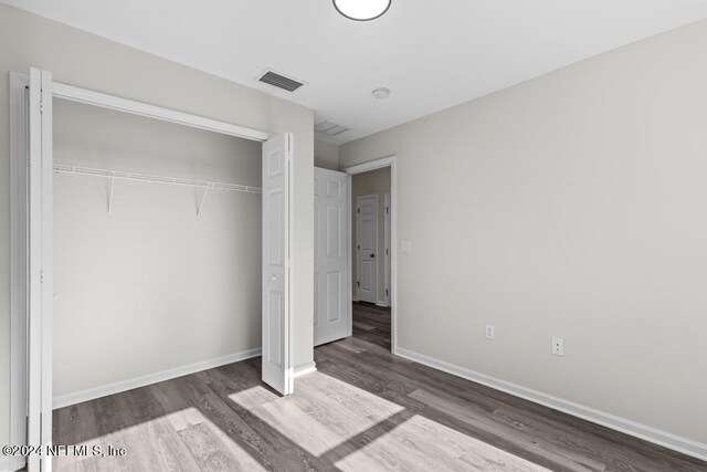 unfurnished bedroom with wood-type flooring and a closet