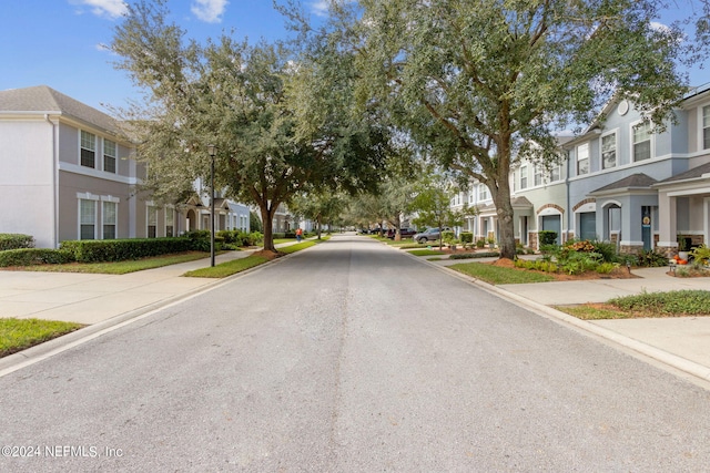 view of road with a residential view, street lights, and sidewalks