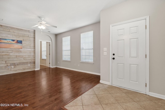 foyer featuring wood walls, light wood-type flooring, and ceiling fan