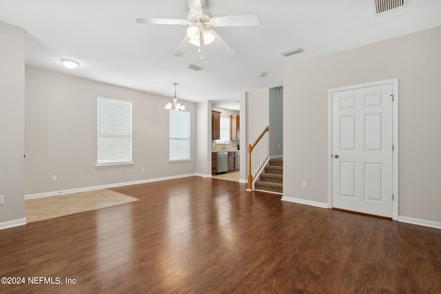 unfurnished living room with visible vents, ceiling fan with notable chandelier, a sink, and wood finished floors