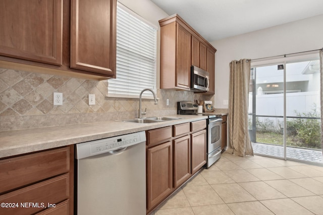 kitchen featuring backsplash, light countertops, brown cabinets, stainless steel appliances, and a sink