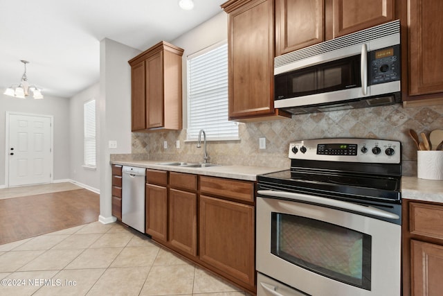 kitchen with appliances with stainless steel finishes, a healthy amount of sunlight, sink, and a chandelier