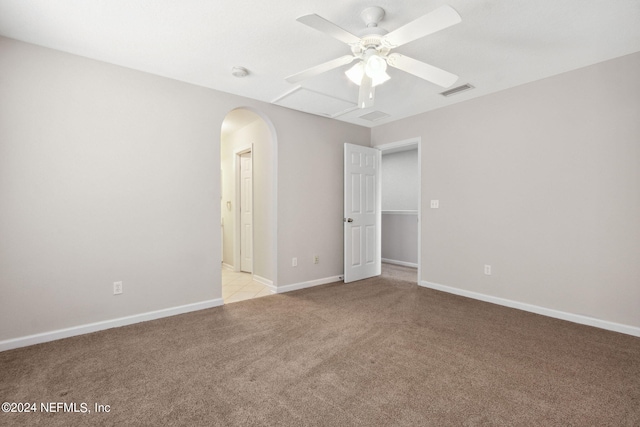 unfurnished room with visible vents, a ceiling fan, arched walkways, baseboards, and light colored carpet