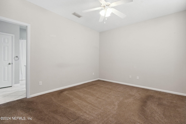 empty room featuring visible vents, baseboards, ceiling fan, light colored carpet, and light tile patterned flooring