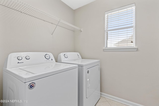 clothes washing area with laundry area, light tile patterned flooring, separate washer and dryer, and baseboards