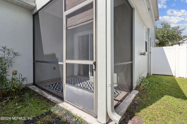 view of side of property with a gate, fence, and stucco siding