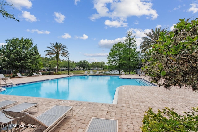 community pool with a patio and fence