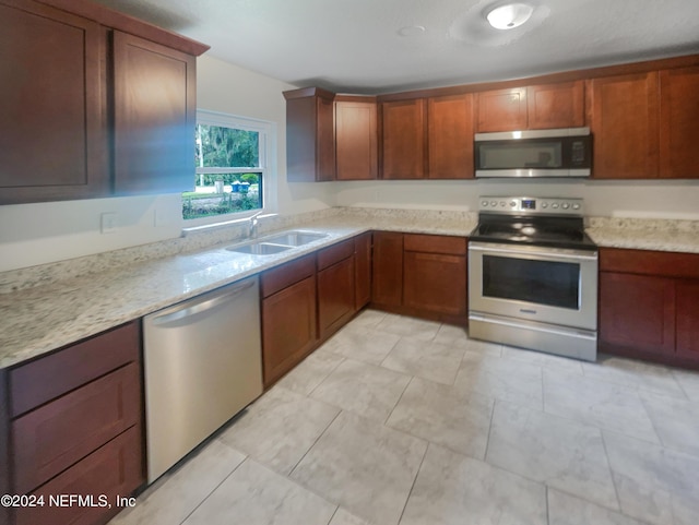 kitchen featuring light stone counters, sink, and stainless steel appliances