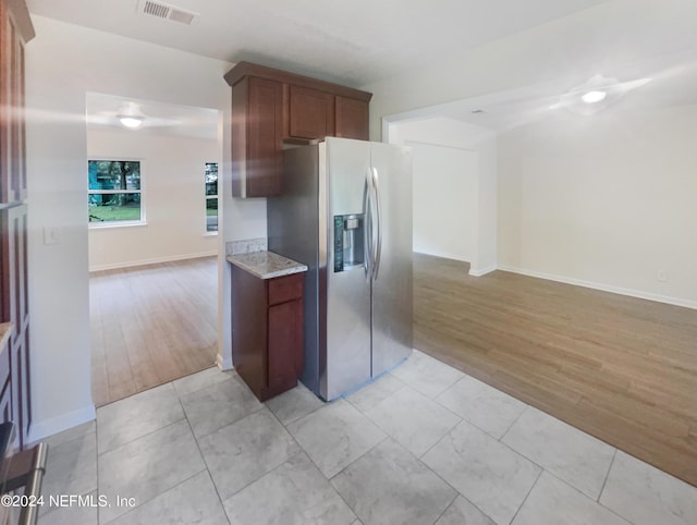 kitchen with light hardwood / wood-style floors, stainless steel fridge with ice dispenser, and light stone countertops