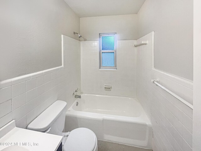 full bathroom with tile walls, toilet, vanity, and tiled shower / bath