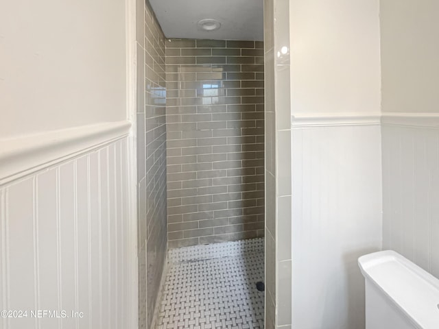 bathroom featuring tiled shower and toilet