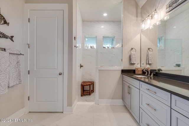 bathroom with a tile shower and vanity