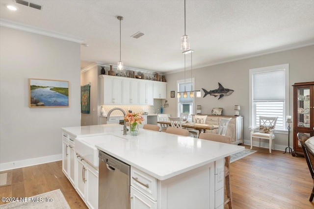 kitchen featuring hanging light fixtures, stainless steel dishwasher, white cabinets, and a center island with sink