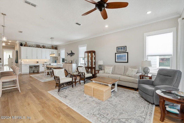 living room featuring ceiling fan, ornamental molding, and light hardwood / wood-style flooring