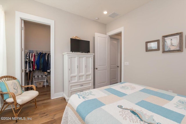 bedroom featuring a walk in closet, hardwood / wood-style floors, and a closet