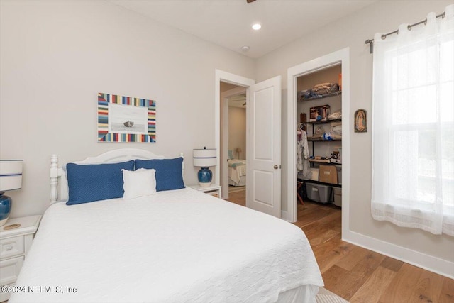 bedroom with a walk in closet, a closet, and light wood-type flooring