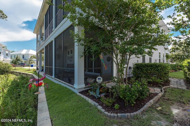 view of side of home with a sunroom and a lawn