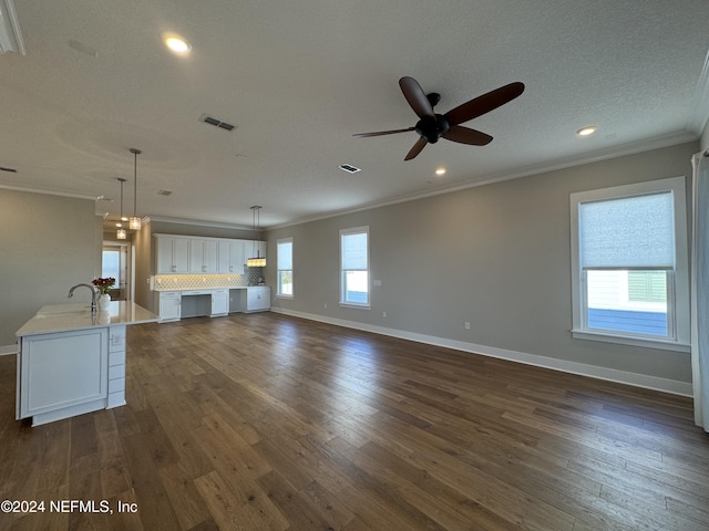 unfurnished living room featuring dark hardwood / wood-style floors, sink, ornamental molding, ceiling fan, and a textured ceiling