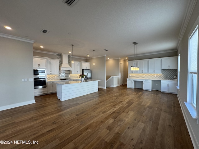 kitchen featuring custom exhaust hood, decorative light fixtures, a center island with sink, appliances with stainless steel finishes, and white cabinets