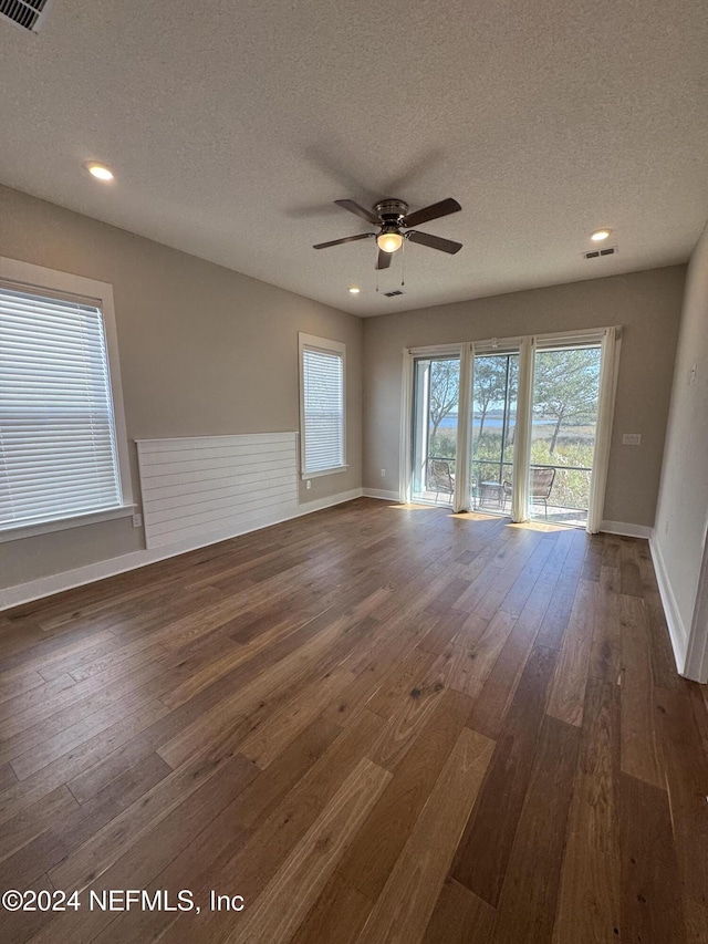 empty room featuring dark wood-type flooring, ceiling fan, and a textured ceiling