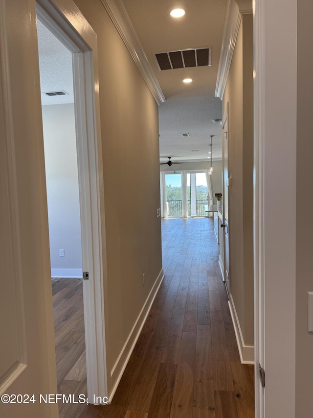 corridor featuring crown molding, dark wood-type flooring, and a textured ceiling