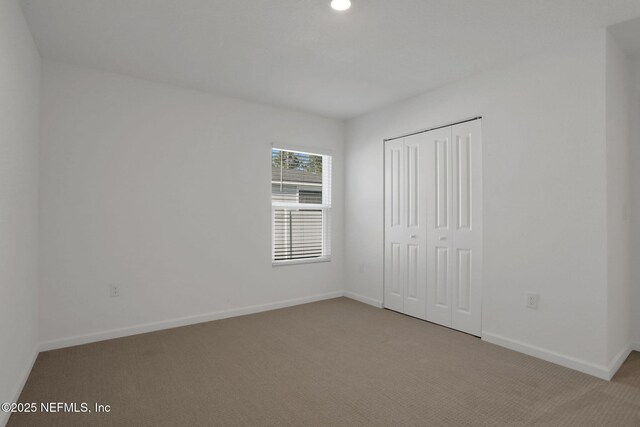 unfurnished bedroom featuring light carpet and a closet